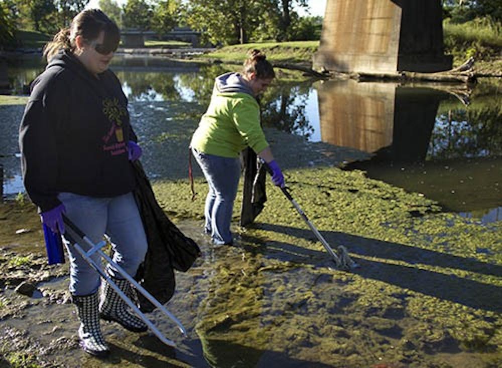 Michelle Elam, a freshman nursing major, picks up a piece of garbage while Natalie Brinson, a CAP freshman, looks for garbage to pick up. Students and community members cleaned the White River on Sept. 14. DN PHOTO EMMA ROGERS