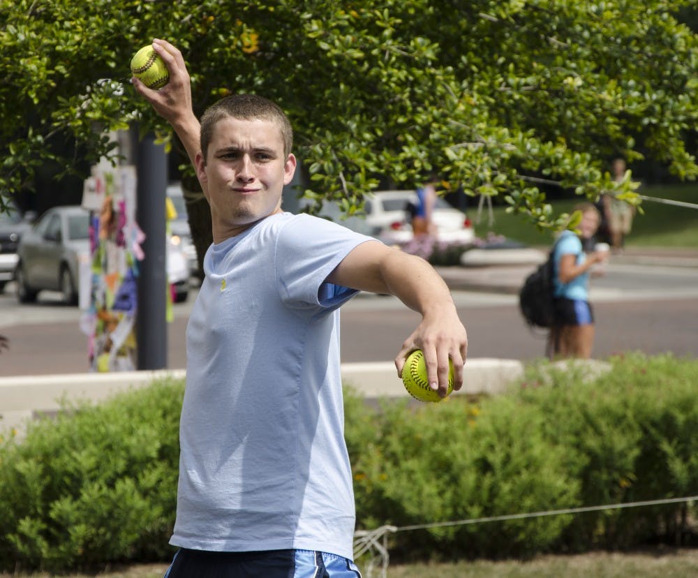 Grady Gaynor, a sophomore sports administration major, winds up for the pitch as he attempts to dunk an officer Aug. 22 at the Scramble Light. DN FILE PHOTO COREY OHLENKAMP