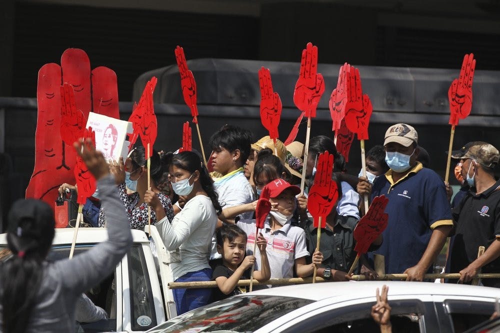 Protesters hold large three-fingered salute cutouts while onboard a vehicle in Yangon, Myanmar on Monday, Feb. 8, 2021. The salutes represent resistance to the military coup that happened last week. (AP Photo)