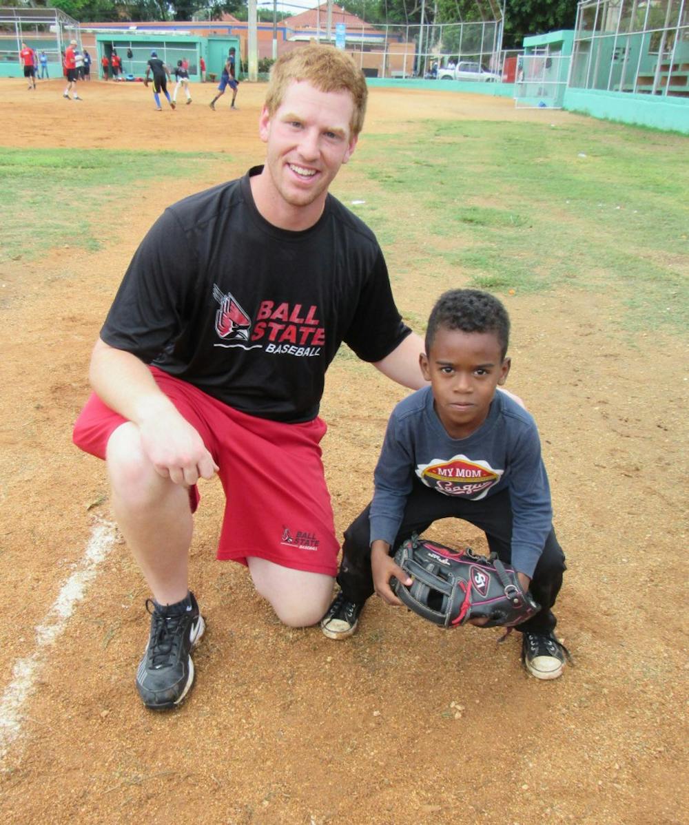 A young Dominican baseball player shows off the new glove given to him by Ball State junior Caleb Stayton. Stayton, as well as the rest of the Cardinals baseball team, spent Thanksgiving break playing baseball and performing community service in the Dominican Republic.