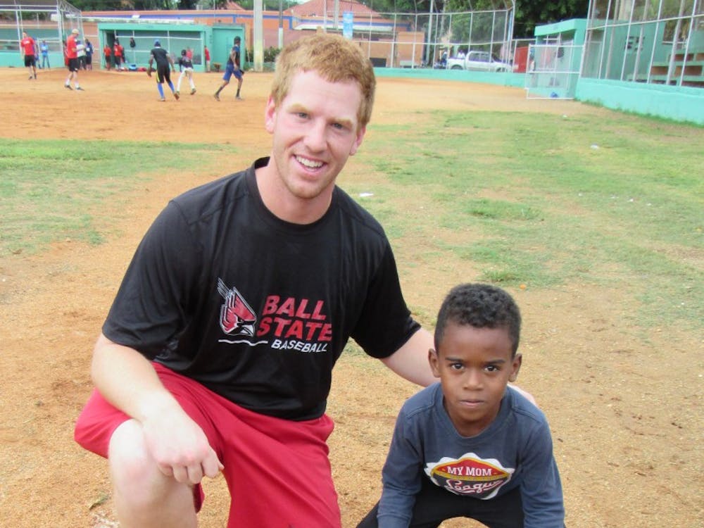 A young Dominican baseball player shows off the new glove given to him by Ball State junior Caleb Stayton. Stayton, as well as the rest of the Cardinals baseball team, spent Thanksgiving break playing baseball and performing community service in the Dominican Republic.