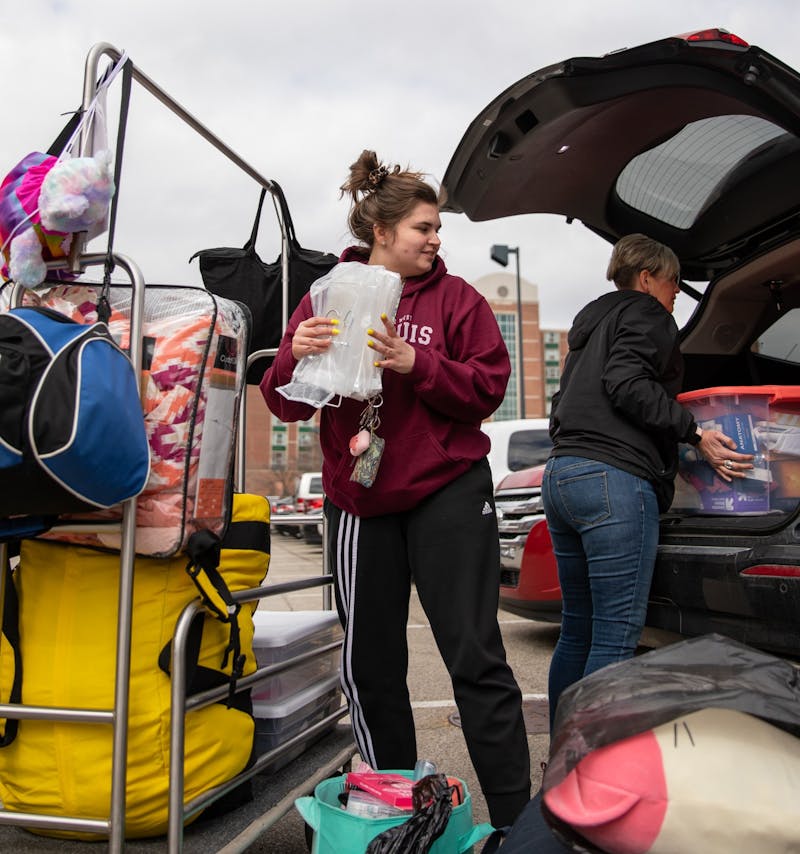 Senior exercise student Danielle Sprouse takes her stuff from the cart to her mom's car March 17, 2020, outside of Park Hall. Multiple students and their families were moving out of all the dorms. Jacob Musselman, DN