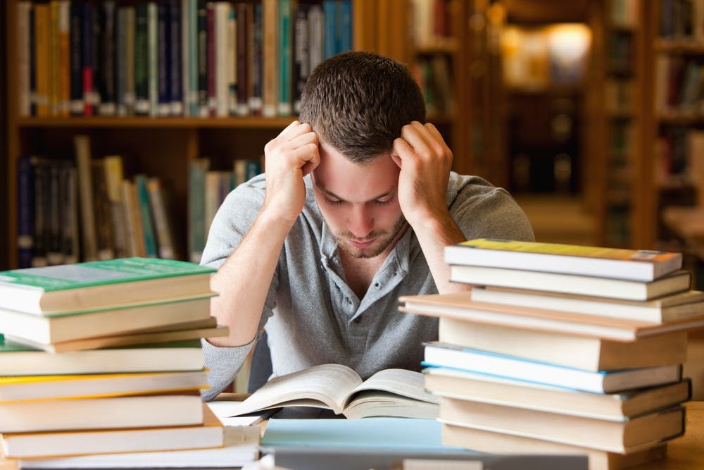 Tired student having a lot to read in a library