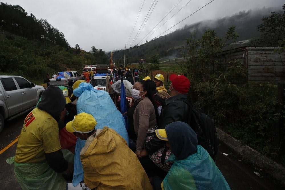 Residents traveling in the bed of a pickup truck wait on a road blocked by debris brought on by a landslide in the aftermath of Hurricane Eta, in Purulha, northern Guatemala Friday, Nov. 6, 2020. As the remnants of Eta moved back over Caribbean waters, governments in Central America worked to tally the displaced and dead, and recover bodies from landslides and flooding that claimed dozens of lives from Guatemala to Panama. (AP Photo/Moises Castillo)