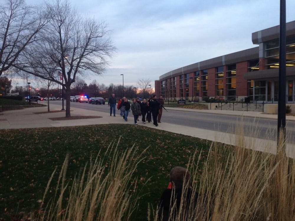 	An officer escorts people from the Student Recreation and Wellness Center. People were sent to the Architecture Building to wait for the all clear after a report of an armed assailant on campus. DN PHOTO JEREMY ERVIN