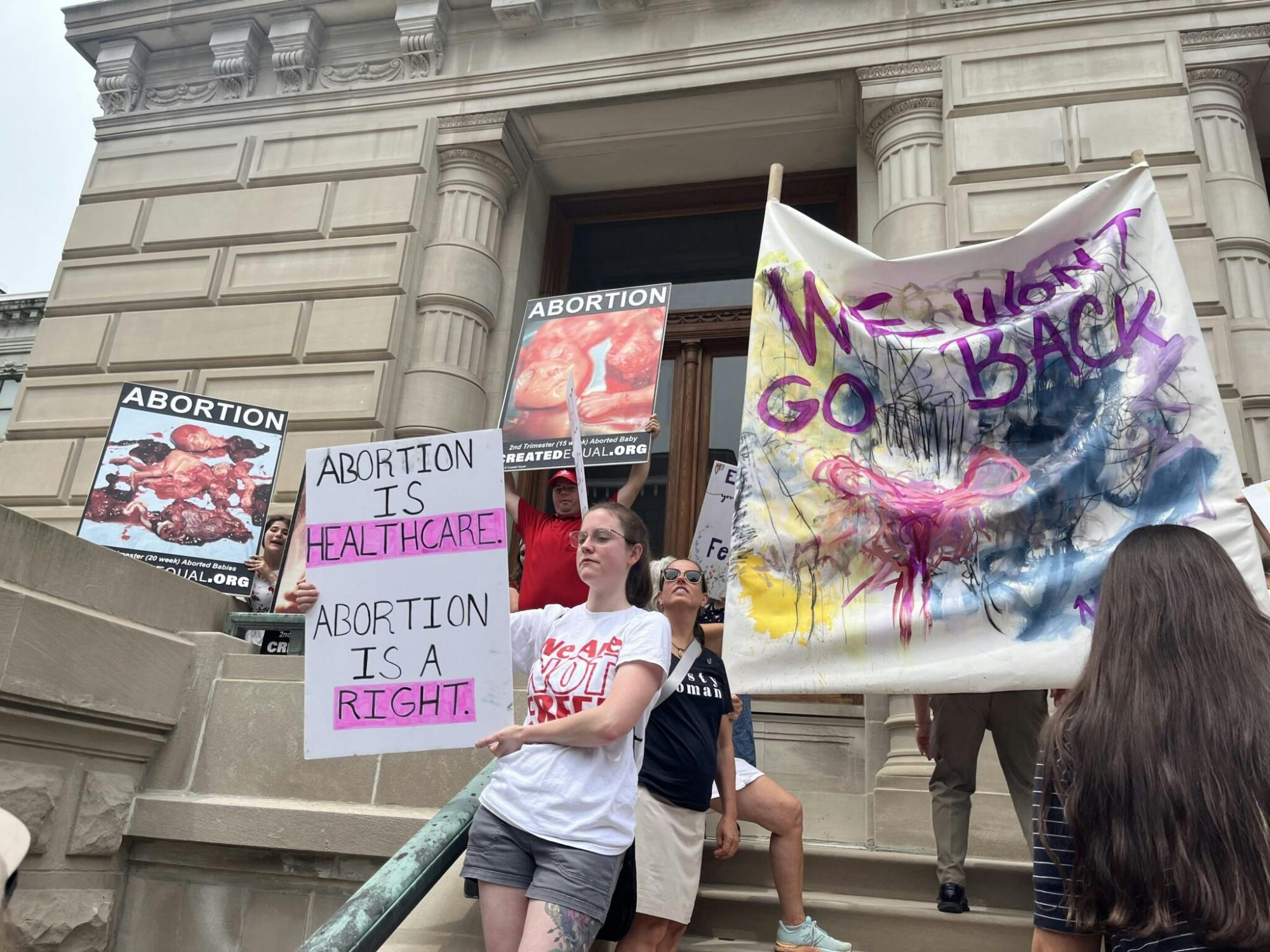 Anti-abortion and abortion rights activists line up on the Indiana Statehouse steps on July 25. (Whitney Downard/Indiana Capital Chronicle)