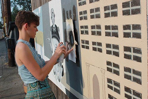 Marta Vitolins, president of Glue & Scissors, spray paints windows onto the mural behind Be Here Now. The mural is the first community project Glue & Scissors started to involve the community in making and celebrating art. DN PHOTO RYAN HOWE