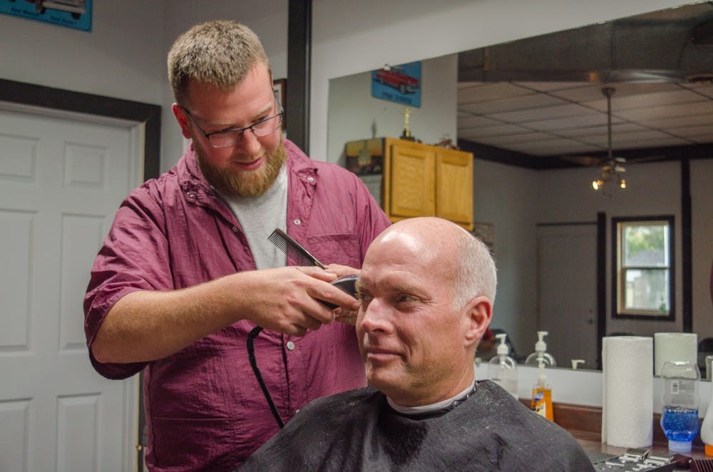 Zach Stratton cuts customer Pete Stafford's hair, on Oct. 23 at his barber shop. Stratton has owned his barber shop for 10 years. Stephanie Amador, DN