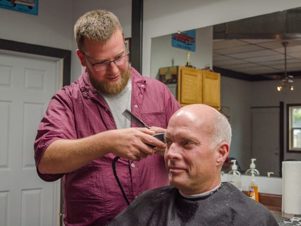 Zach Stratton cuts customer Pete Stafford's hair, on Oct. 23 at his barber shop. Stratton has owned his barber shop for 10 years. Stephanie Amador, DN