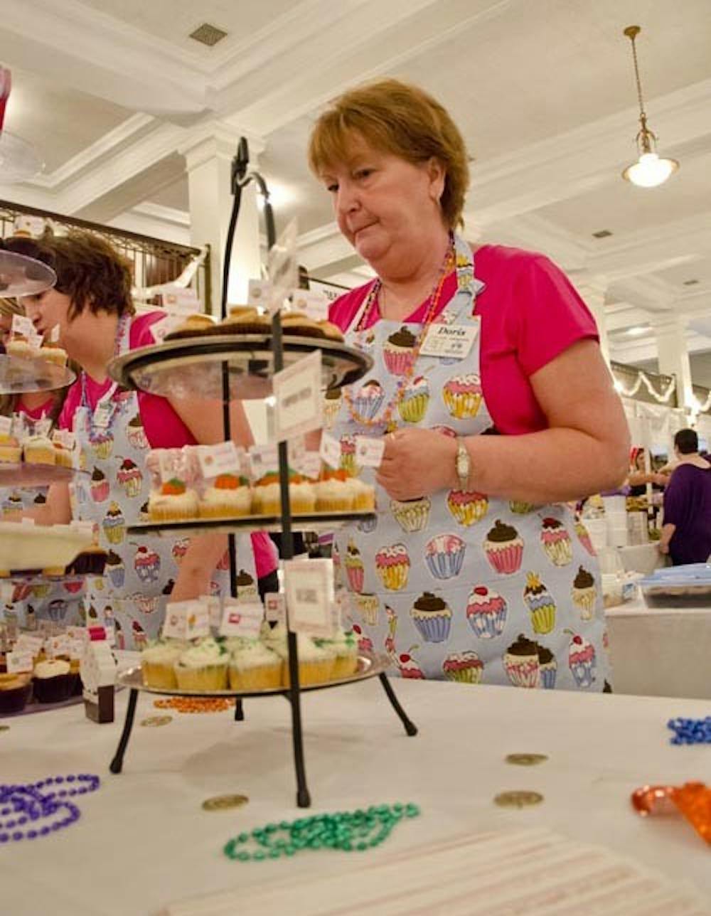 Doris Shaw works to keep the display towers for Cardinal Cupcakes and Coneys April 15, 2012, at the Taste of Muncie. The store’s new hours are 6 p.m. to 2 a.m. Thursday, Friday and Saturday. DN FILE PHOTO COREY OHLENKAMP