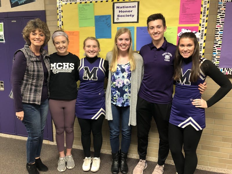 Lisa Letsinger, adviser of Muncie Central High School's chapter of National Honor Society (NHS), stands with Tara Horst, NHS president; Madeline Evans, NHS secretary; Allison Polk, NHS Treasurer; Erich Ong, NHS service hours coordinator; and Megan Clifford, NHS event coordinator, in front of a bulletin board where students can sign up for volunteer opportunities. Kayla Jackson, DN&nbsp;