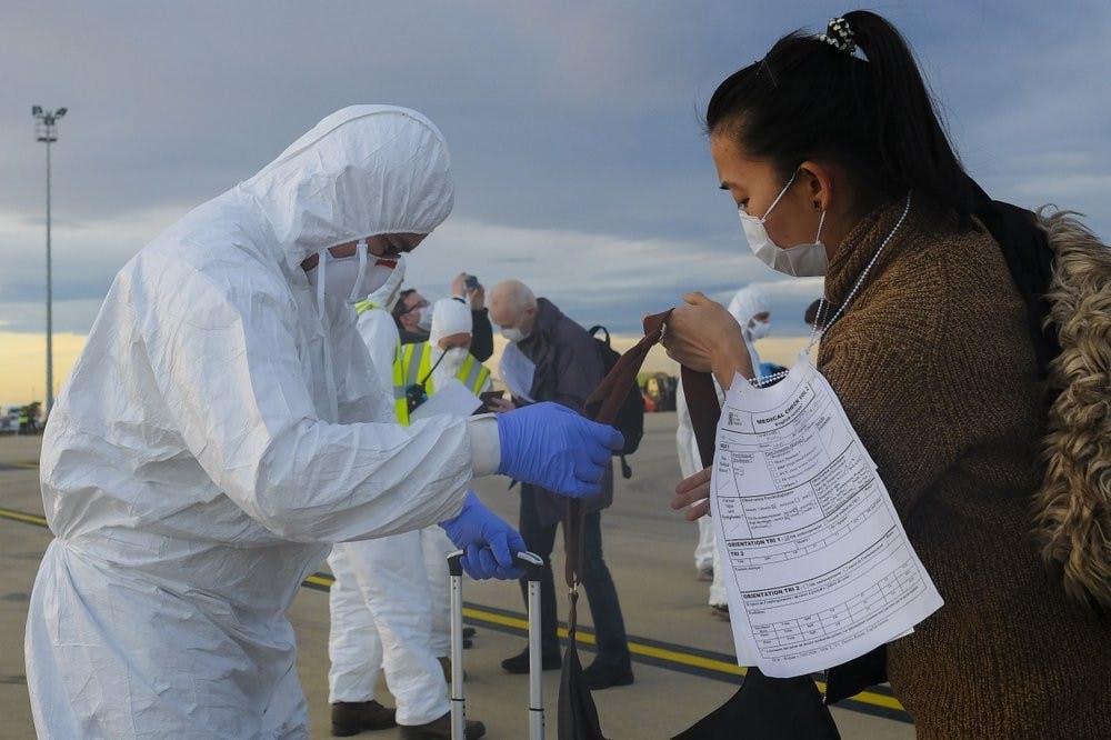In this Feb. 2, 2020, photo, a worker wearing a protective suit checks the luggage of an evacuee from Wuhan, China, after their evacuation flight landed at an airport in Marseilles, France. China sent medical workers and equipment Monday to its just-completed, 1,000-bed hospital for treating victims of a new virus that has caused 362 deaths and more than 17,300 infections at home and abroad. (AP Photo/Arek Rataj)