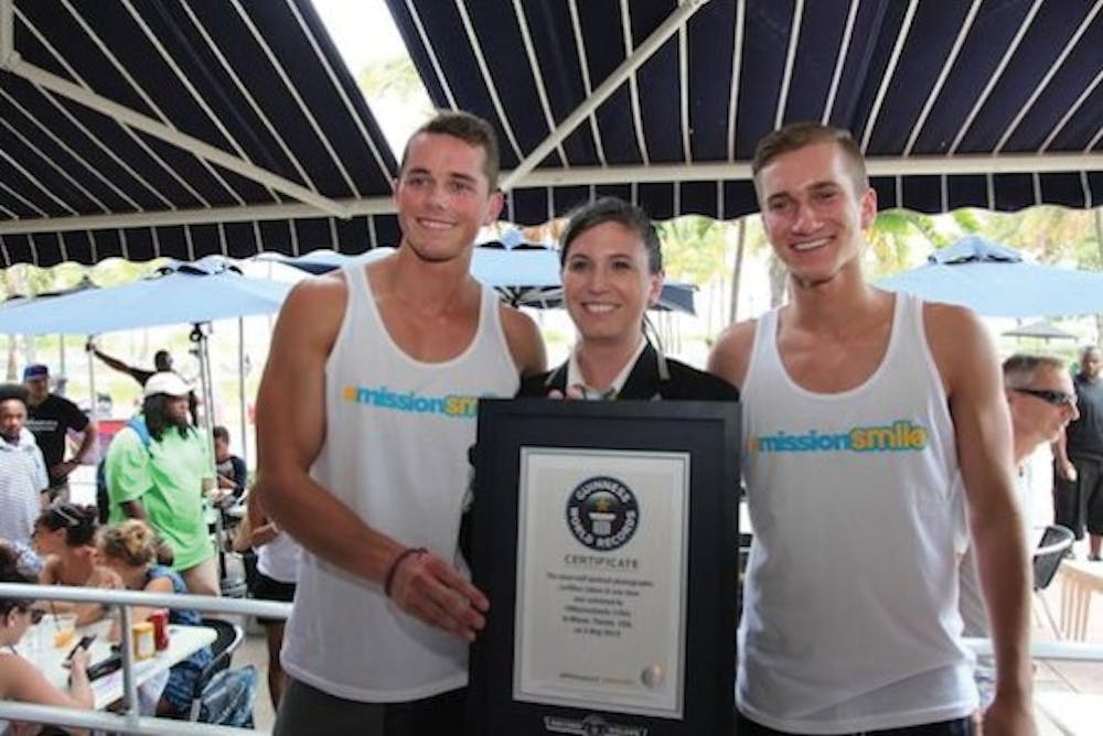 Alumnus Mark E. Miller and Indiana University student Ethan Hethcote pose with a Guinness World Records official after taking 355 selfies with strangers in an hour May 3 at Miami