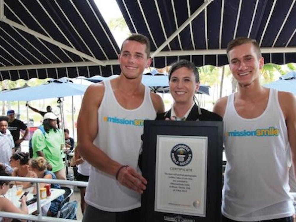Alumnus Mark E. Miller and Indiana University student Ethan Hethcote pose with a Guinness World Records official after taking 355 selfies with strangers in an hour May 3 at Miami