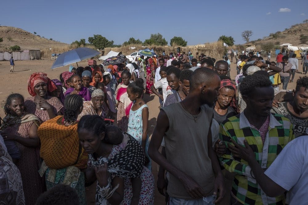 Tigranyan men and women who fled the conflict in Ethiopia's Tigray region, wait in line to receive aid, at Umm Rakouba refugee camp in Qadarif, eastern Sudan, Saturday, Dec. 5, 2020. (AP Photo/Nariman El-Mofty)