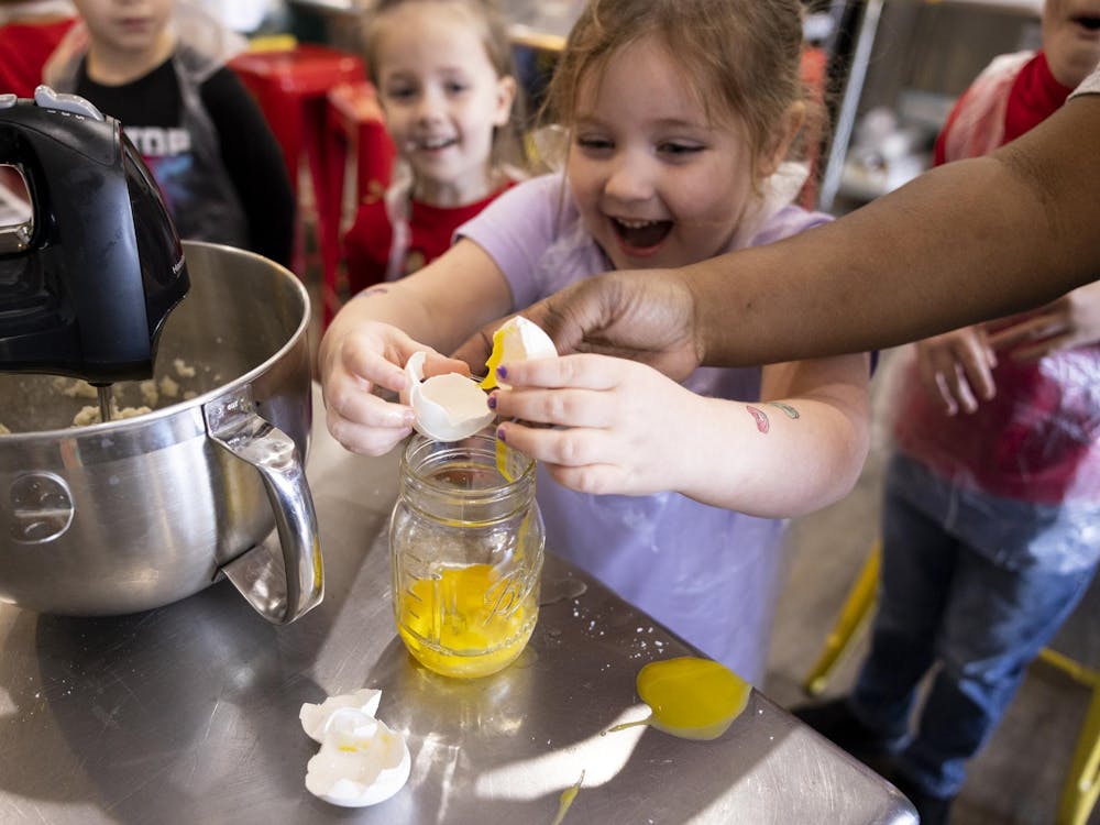 Carys Buzzard cracks an egg, with some spill, into a jar for her cookie dough batter for Santa at Now You're Cooking Culinary on Dec. 23, 2023 in Chesapeake, Virginia. (Billy Schuerman / The Virginian-Pilot)