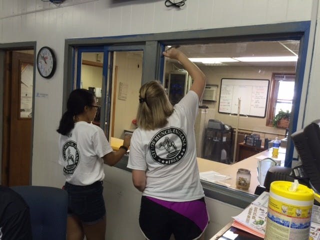 Two high school students touch up the trim around an office window at the Boys and Girls Club. PHOTO BY MICHAEL KUHN