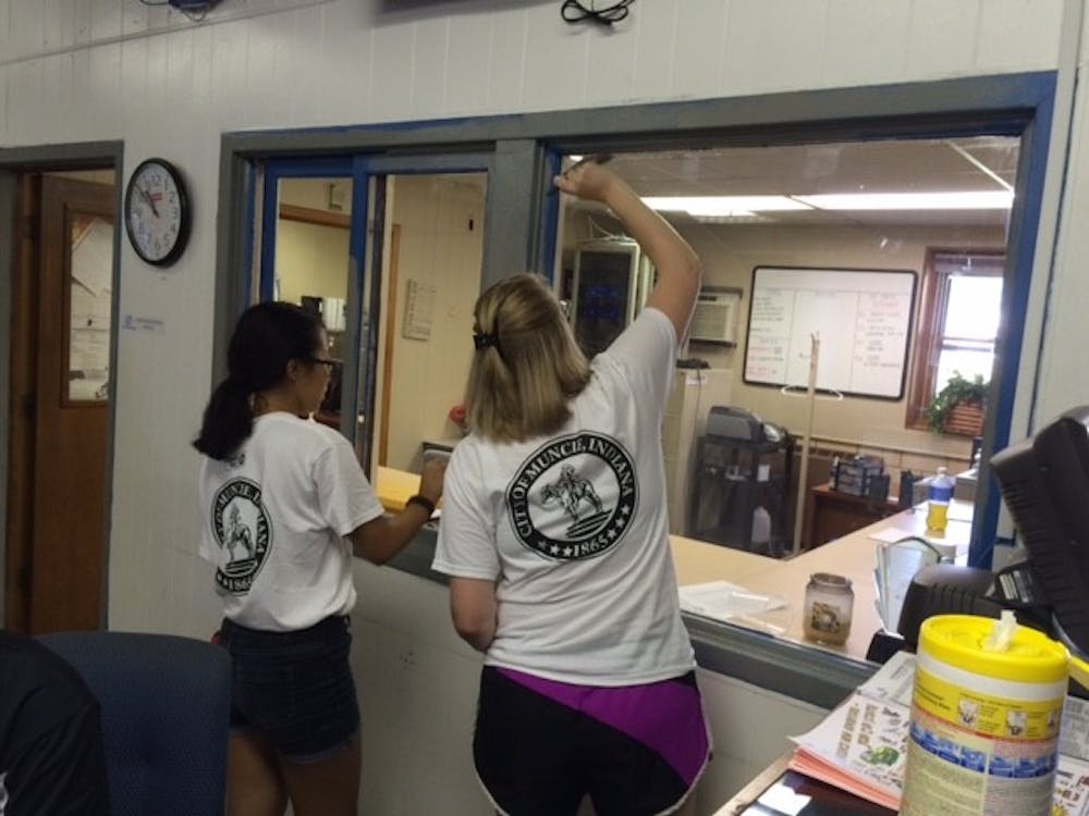 <p>Two high school students touch up the trim around an office window at the Boys and Girls Club. <em>PHOTO BY MICHAEL KUHN</em></p>