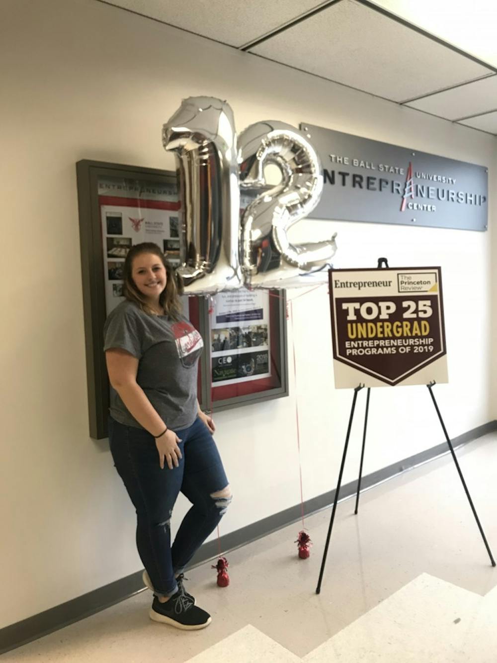 <p>Entrepreneurship major Kyli Penrod poses in front of balloons and signs celebrating the Ball State program's ranking. The entrepreneurship program is ranked 12th in the nation by the Princeton Review and Entrepreneur magazine.<strong> Kyli Penrod, Photo Provided</strong></p>