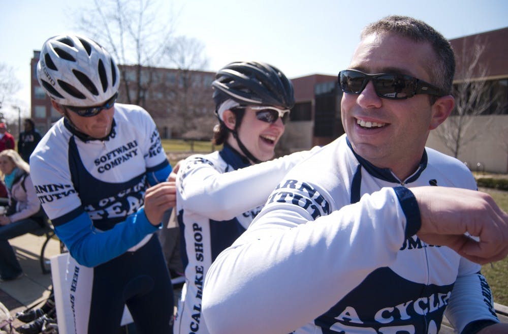 Andy Payne, a cycling team member, has his number pinned on by Rebecca Zink while Connor O