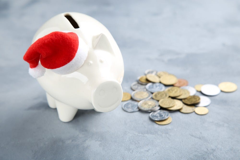 Piggybank with santa hat and coins on grey background