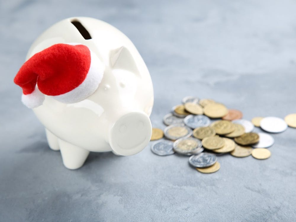 Piggybank with santa hat and coins on grey background