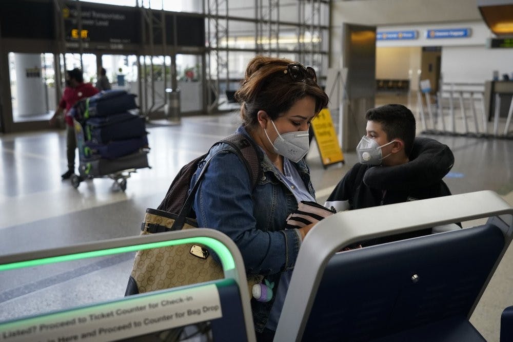 Esmeralda Elizalde checks in for her flight to Mexico at the Los Angeles International Airport in Los Angeles, Monday, Nov. 23, 2020. About 1 million Americans a day packed airports and planes over the weekend even as coronavirus deaths surged across the U.S. and public health experts begged people to stay home and avoid big Thanksgiving gatherings. (AP Photo/Jae C. Hong)