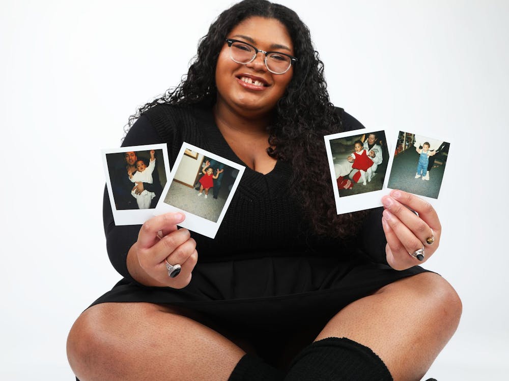 Fourth-year journalism major Emma Plank holds up photos of her as a baby Dec. 1 at the photojournalism studio in the Art and Journalism Building. Mya Cataline, DN