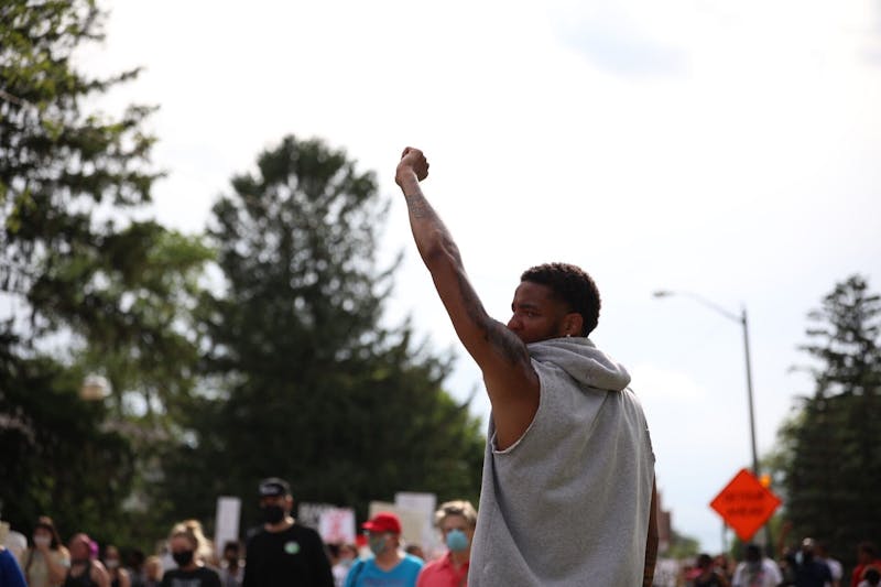 Ishmael El-Amin, junior Ball State Basketball guard, hold his fist in the air while the peaceful protest marches by, June 4, 2020, on University Avenue. The protesters marched from Shafer Tower to Muncie City Hall. Jacob Musselman, DN