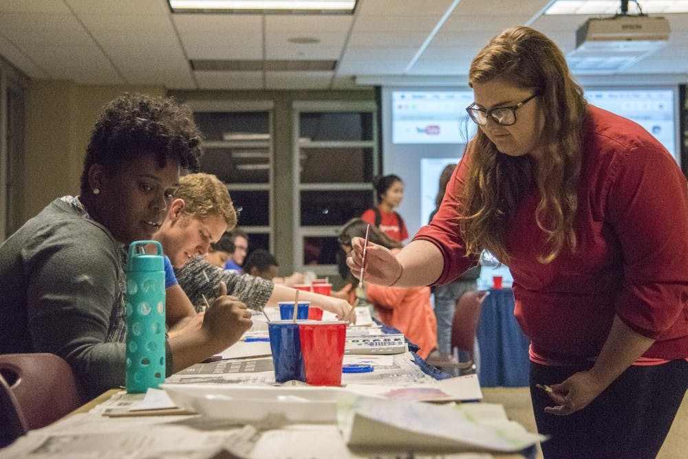 Shelli Burnworth, a junior painting and biology major, teachers a student water painting techniques. Burnworth was asked by the Asian American Student Association to help out at their event. DN PHOTO RACHEL BRAMMER
