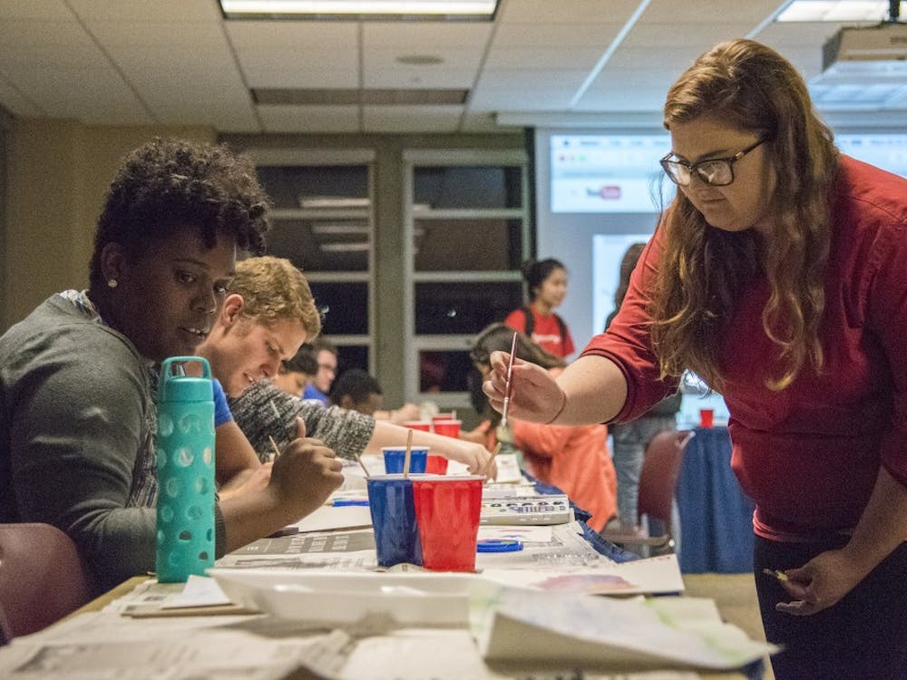 Shelli Burnworth, a junior painting and biology major, teachers a student water painting techniques. Burnworth was asked by the Asian American Student Association to help out at their event. DN PHOTO RACHEL BRAMMER