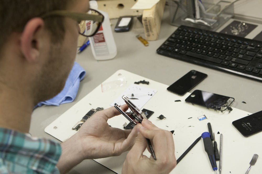 Tyler Little, a junior information system major, works on a phone at MDtekk in Muncie. The business repairs and customizes phones. DN PHOTO JORDAN HUFFER