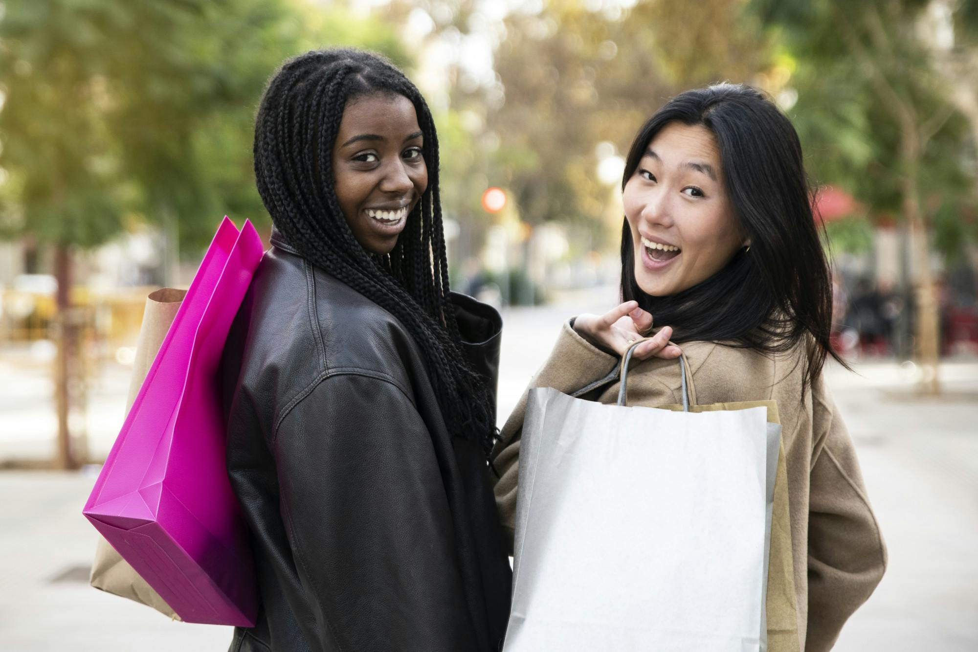 Rear view of two women walking in street for shopping - Pepople multiracial friendship concept - High quality photo