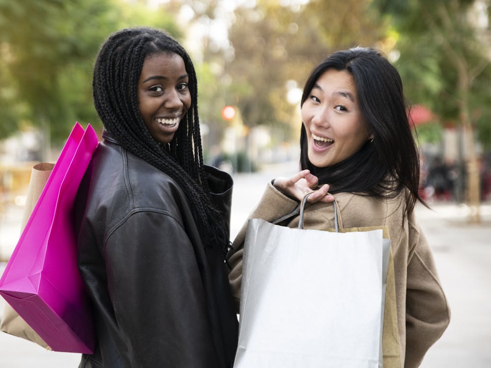 Rear view of two women walking in street for shopping - Pepople multiracial friendship concept - High quality photo