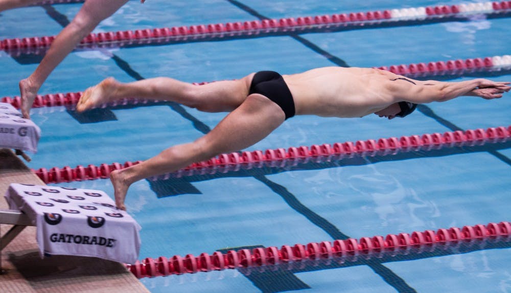 Junior Neal Fennig launches off the platform in the men's 50-yard freestyle. DN PHOTO KATIE GRAY