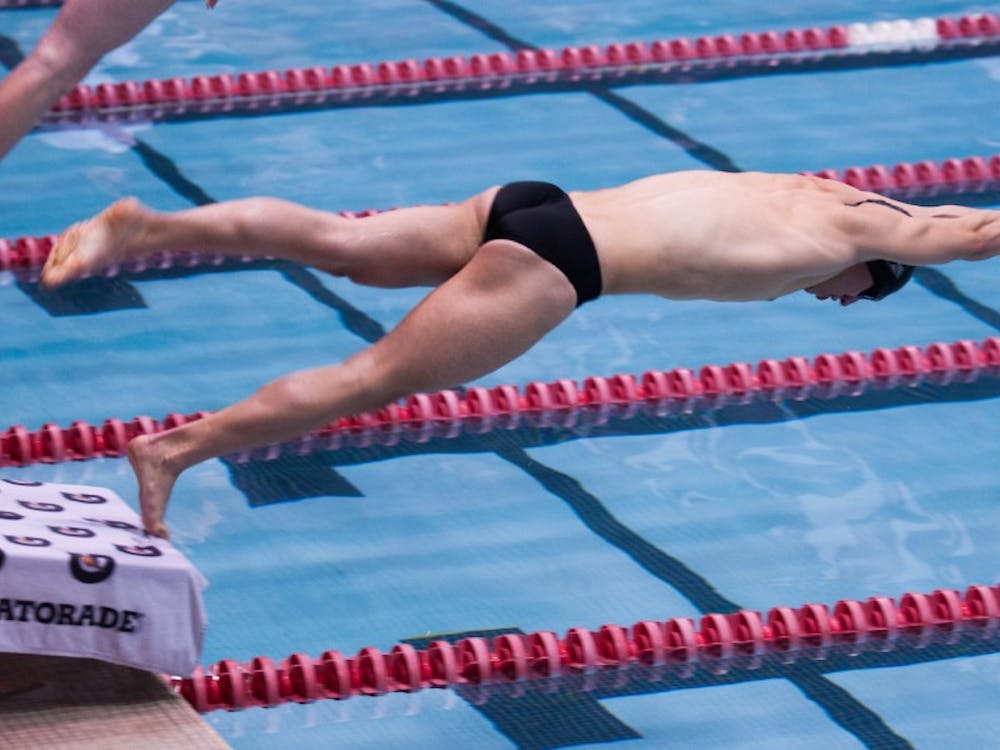 Junior Neal Fennig launches off the platform in the men's 50-yard freestyle. DN PHOTO KATIE GRAY