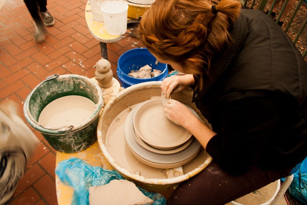 Arielle Day, a senior clay guild major, shows how to make pottery on Oct. 1 at the ArtsWalk in downtown Muncie. DN PHOTO KAITI SULLIVAN