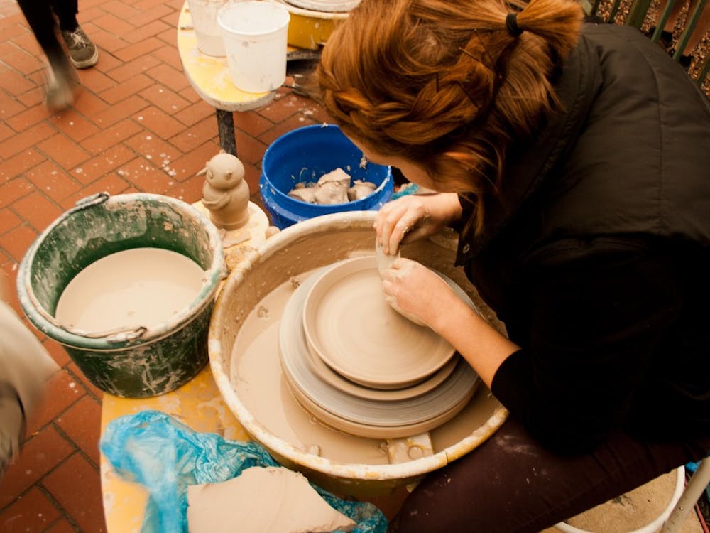 Arielle Day, a senior clay guild major, shows how to make pottery on Oct. 1 at the ArtsWalk in downtown Muncie. DN PHOTO KAITI SULLIVAN