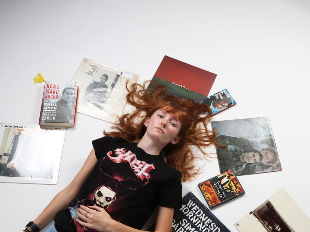 Opinion editor and second-year journalism major Kate Farr poses for a photo surrounded by some of her favorite music items while wearing a Ghost tour T-shirt Sept. 25 in the photojournalism studio. Mya Cataline, DN