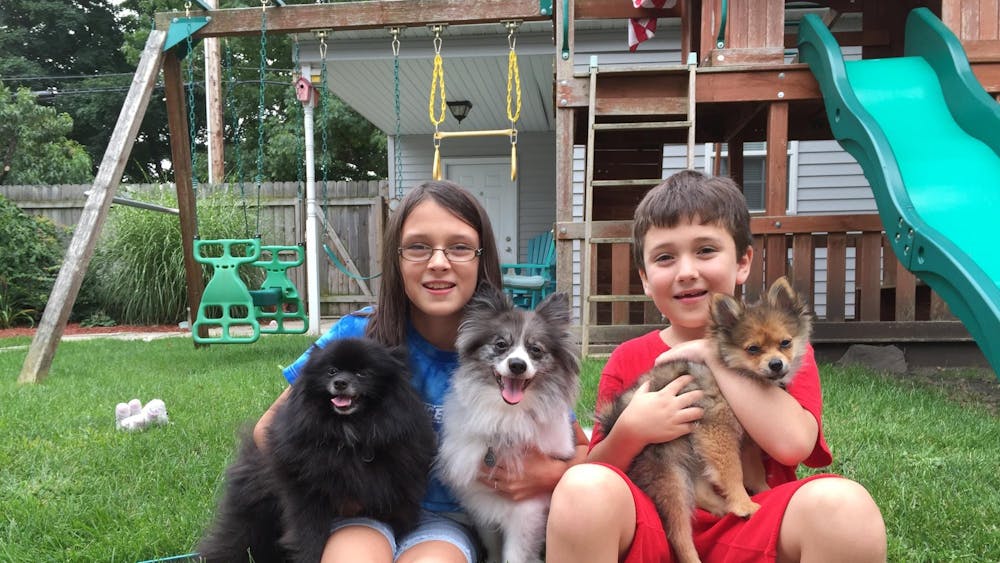 Katherine Hill sitting with her younger brother, Douglas, in their backyard holding their three dogs in August 2015. Katherine Hill, Photo Provided
