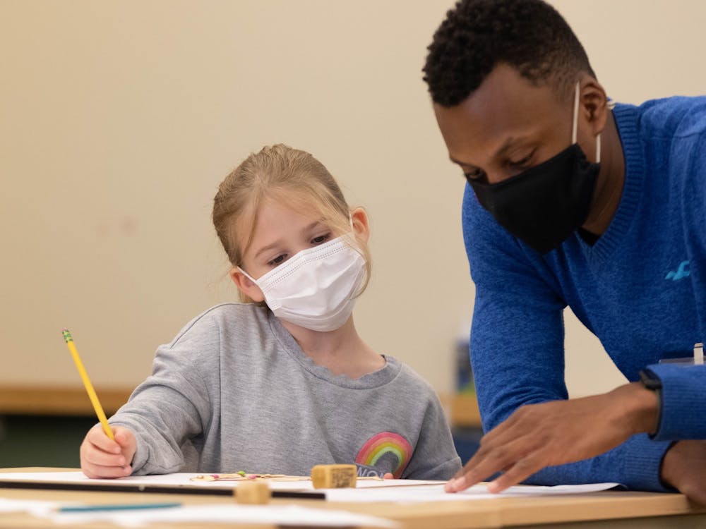 Sarah Waters works with Dominick Haskins, art education major, on her artwork during Saturday Children's Art Classes in the Art and Journalism Building Nov. 13. Eli Houser, DN 