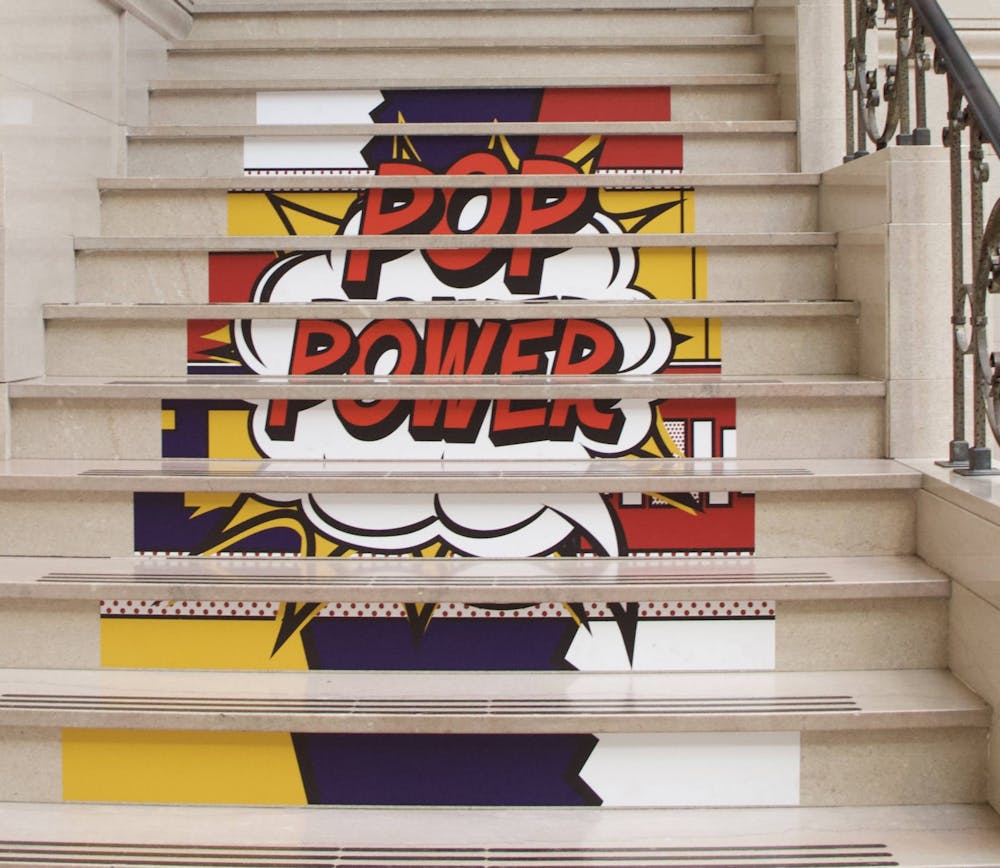 <p>&quot;POP Power&quot; stickers sit on the stairs of the David Owsley Museum of Art (DOMA) May 11, 2021. DOMA Director Robert La France said staff wanted to experiment with stickers leading people to the second floor of the special exhibition instead of signs with arrows. <strong>Grace McCormick, DN</strong></p>