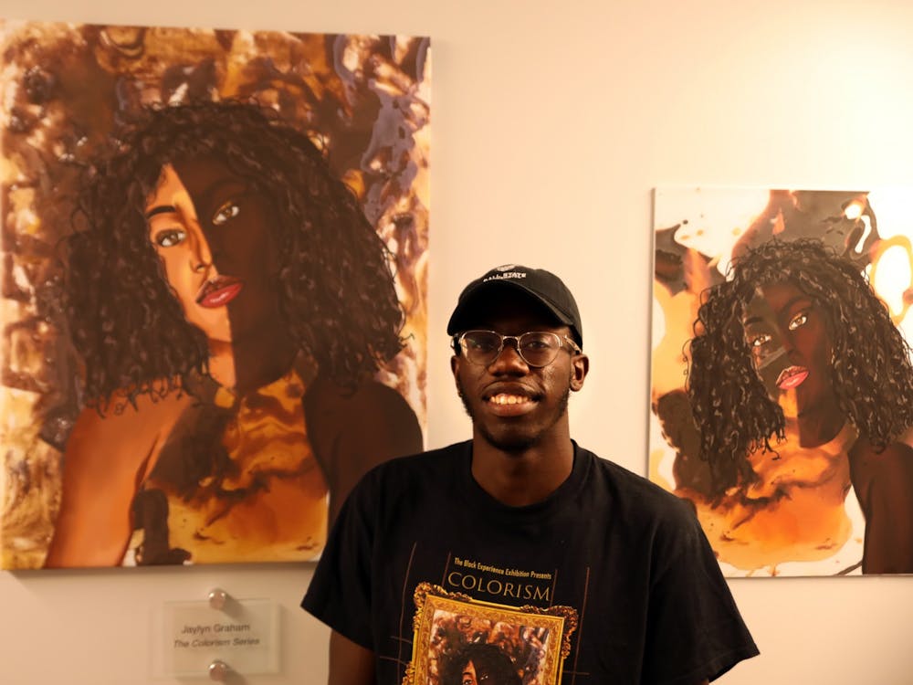 Jaylyn Graham poses for a photo next to his artwork &quot;The Colorism Series,&quot; Sept. 13 in the Multicultural Center. The piece was part of Graham&#x27;s senior exhibition &quot;The Black Experience.&quot; Rylan Capper, DN