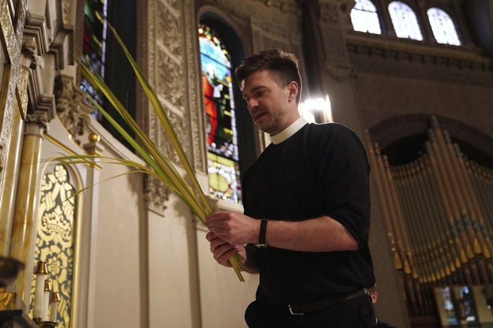 In this March 29, 2020, photo, Rev. Steven Paulikas decorates an altar with palm fronds for Palm Sunday, which was commemorated virtually at All Saints' Episcopal Church in the Brooklyn borough of New York. The global coronavirus pandemic is upending the season's major religious holidays, forcing leaders and practitioners across faiths to improvise. (AP Photo/Emily Leshner)