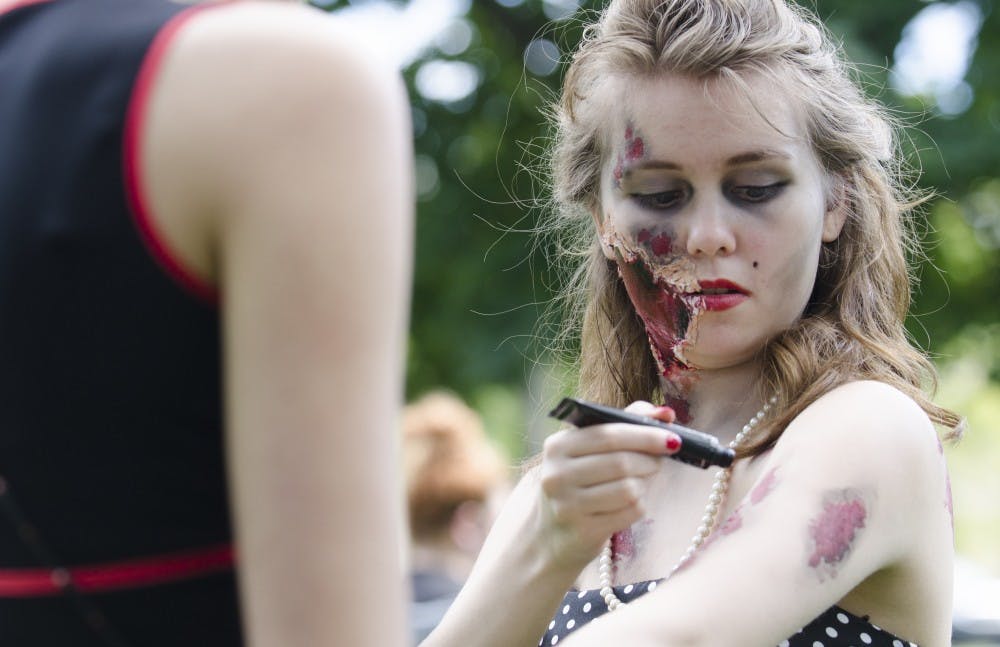 Beverly Stroud, 19, applies fake blood before the zombie walk on Sept. 27 at the Quad. DN PHOTO BREANNA DAUGHERTY