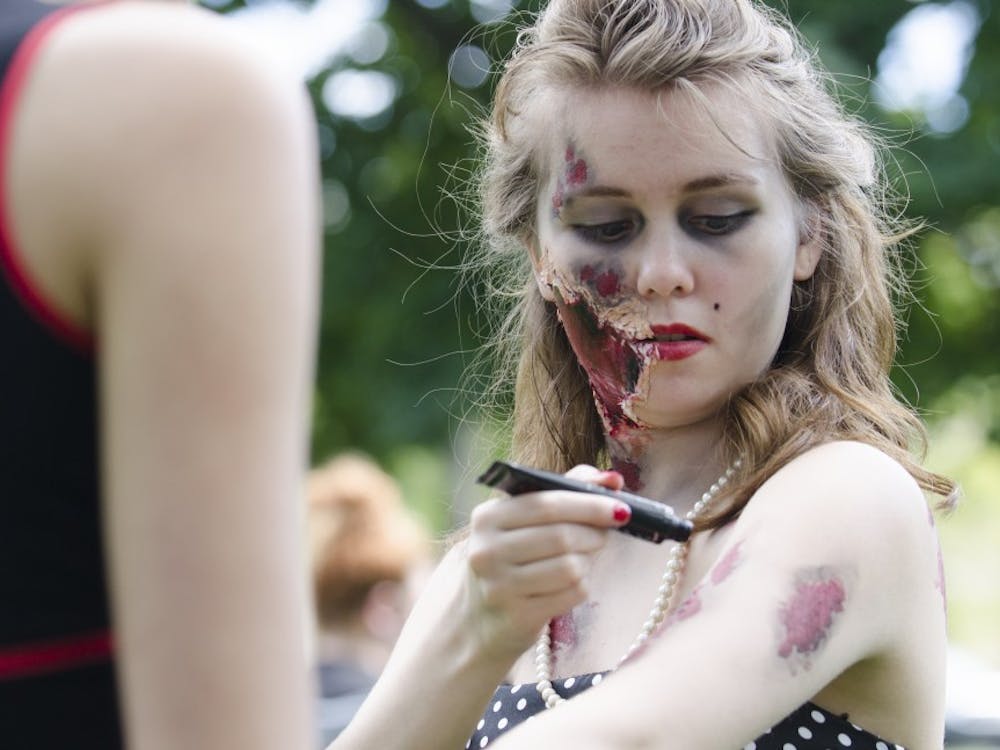 Beverly Stroud, 19, applies fake blood before the zombie walk on Sept. 27 at the Quad. DN PHOTO BREANNA DAUGHERTY
