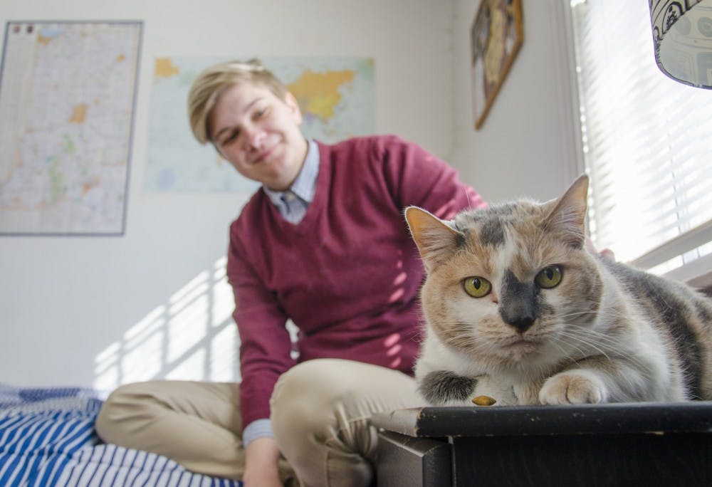 Carli Hendershot, a junior political science major, pets her 13-year-old calico cat, Callie, at her home. Hendershot credits Callie with helping her through depression. Callie was always there when she needed her. DN PHOTO BREANNA DAUGHERTY