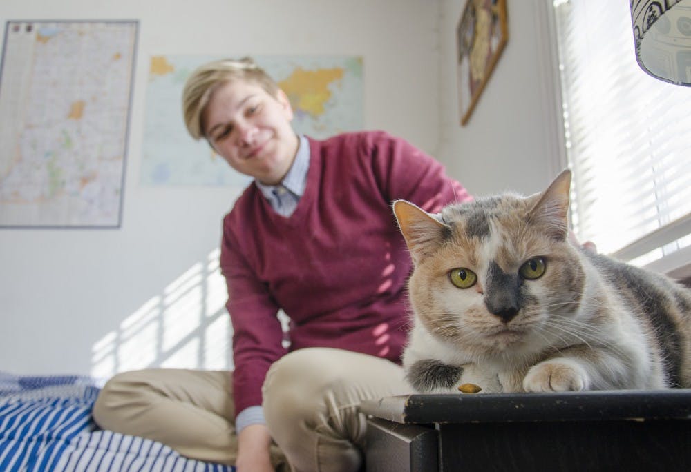 <p>Carli Hendershot, a junior political science major, pets her 13-year-old calico cat, Callie, at her home. Hendershot credits Callie with helping her through depression. Callie was always there when she needed her. <em>DN PHOTO BREANNA DAUGHERTY</em></p>