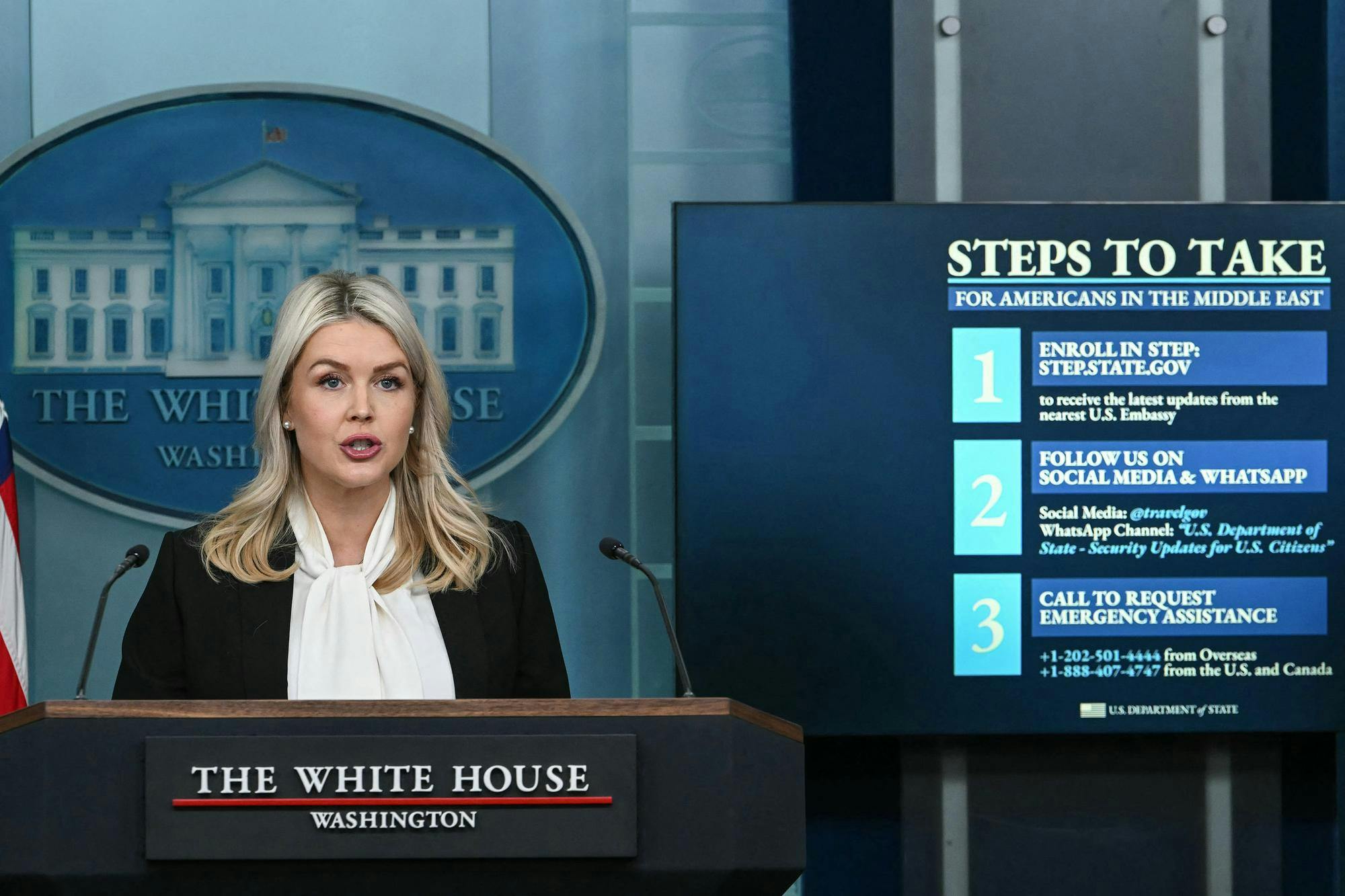 White House Press Secretary Karoline Leavitt speaks alongside a screen displaying information for US citizens seeking assistance in the Middle East, during a press briefing in the Brady Briefing Room of the White House in Washington, DC, on March 4, 2026. President Donald Trump will attend a ceremony marking the return of American troops killed during the war on Iran, Leavitt said Wednesday. (Photo by ANDREW CABALLERO-REYNOLDS / AFP via Getty Images)