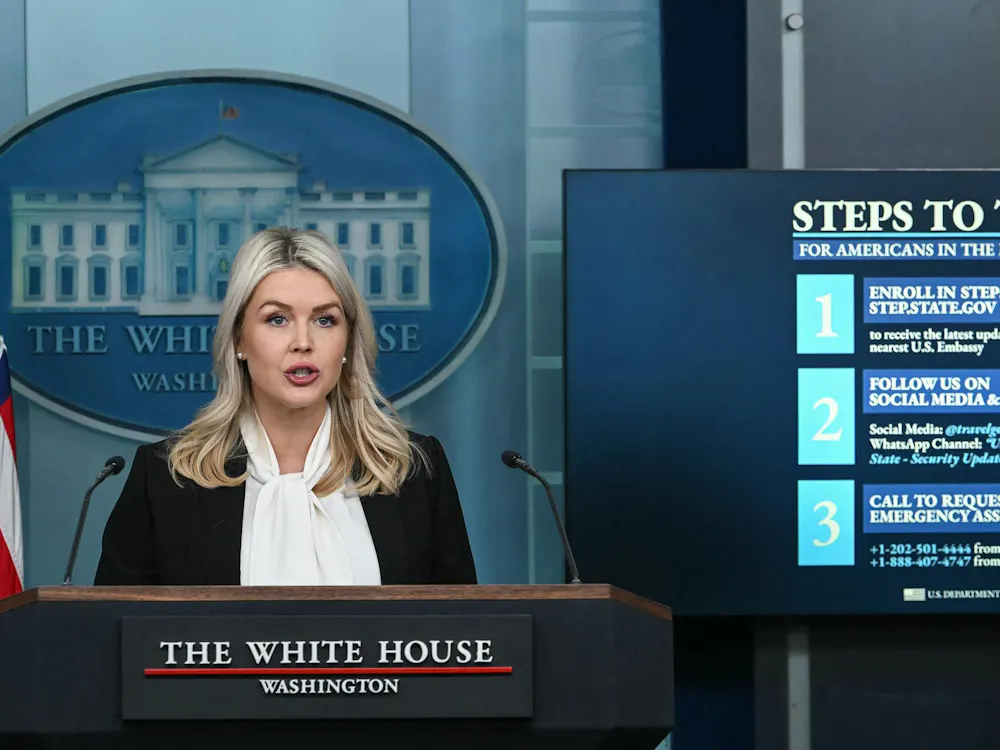 White House Press Secretary Karoline Leavitt speaks alongside a screen displaying information for US citizens seeking assistance in the Middle East, during a press briefing in the Brady Briefing Room of the White House in Washington, DC, on March 4, 2026. President Donald Trump will attend a ceremony marking the return of American troops killed during the war on Iran, Leavitt said Wednesday. (Photo by ANDREW CABALLERO-REYNOLDS / AFP via Getty Images)
